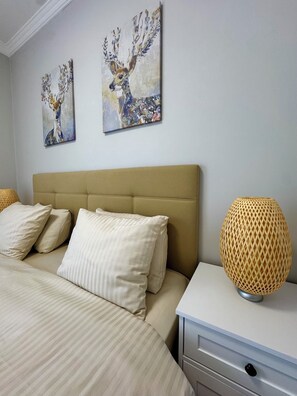A bedroom with a bed, pillows, a headboard, a bedside table with a lamp, and two wall-mounted paintings. - Stylish Taksim 360 Apartment in Central Istanbul (Beyoğlu)