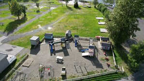 An aerial view of a campground with multiple cabins, a playground, and a dock by a lake. - Lillehammer Camping (Lillehammer)
