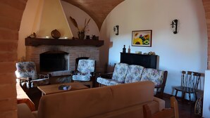 Una sala de estar acogedora con chimenea, sillones estampados y un sofá.