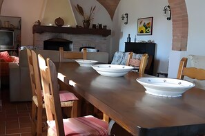 Un espace repas avec une longue table en bois, des chaises et des bols décoratifs blancs.