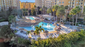 A resort pool area with a ship-shaped water feature, lounge chairs, and palm trees. - 2BR Fireworks View With Pool Spa 5 Minutes to Disney (Orlando)