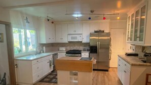 A modern kitchen with white cabinets, a stainless steel refrigerator, a microwave, and a gas stove. - Mid-century Ojai Escape Hot Tub Serene Garden (Ojai)