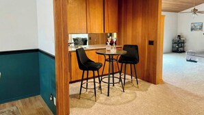 A compact kitchen with wooden cabinets, a small dining area with two black chairs, and a ceiling fan. - Mid-century Ojai Escape Hot Tub Serene Garden (Ojai)