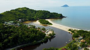 An aerial view of a coastal area with a beach, a small island with buildings, and a large body of water. - Casa Alto Padr o com 5 Su tes e Jacuzzi Privativa (São Sebastião)