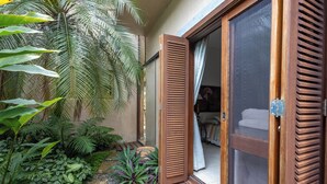 Una terraza de madera con un ventanal corredizo que da a un dormitorio.