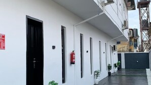 Un bâtiment propre et moderne, avec des murs blancs et une porte noire. On y trouve plusieurs fenêtres et un extincteur fixé au mur.