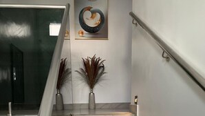 Un escalier moderne avec des marches en marbre, une rampe en verre et des vases décoratifs.