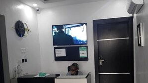 Un comptoir d ’accueil avec un téléviseur fixé au mur, une horloge et une porte.