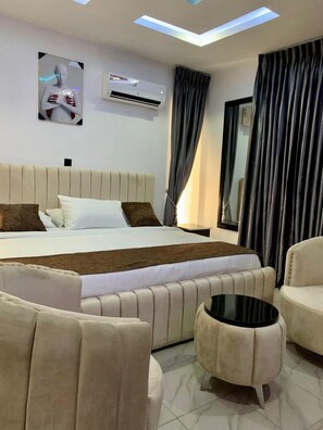 A modern hotel room with a large bed, a flat-screen TV, a ceiling light, and a window with curtains. - Grand Churchill Luxury Hotel (Lagos)