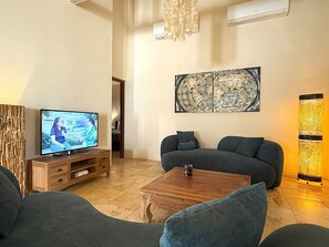 Ein Wohnzimmer mit Fernseher, Sofas, einem Couchtisch und einer Wanddekoration.