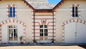 A two-story building with a symmetrical facade, featuring a central entrance with a decorative archway, flanked by two windows on each side. - Maison Adrienne / Chambre beige Charming guest house, 4 km from Beauval Zoo (Saint-Aignan)