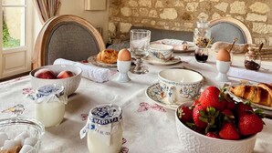 A breakfast table set with eggs, pastries, and fruit, in a room with stone walls and a window with curtains. - Maison Adrienne / Chambre beige Charming guest house, 4 km from Beauval Zoo (Saint-Aignan)