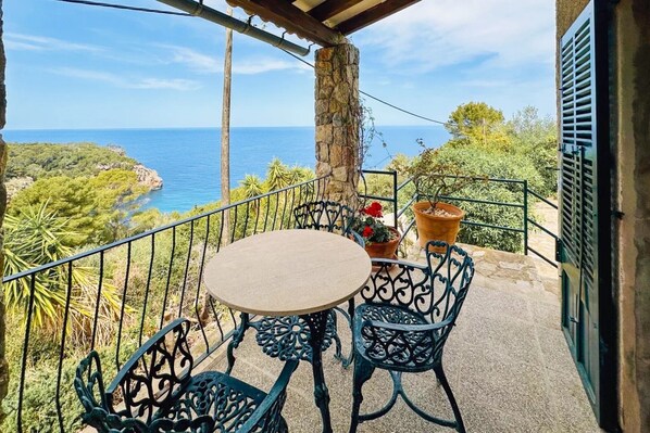 Un balcon avec une table et des chaises, donnant sur un paysage côtier.