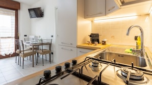 Een moderne keuken met een gasfornuis, een spoelbak en een eethoek met een tafel en stoelen.