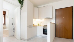 Een moderne keuken met witte kastjes, een houten deur en een wasmachine in de hoek.
