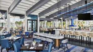 Un ristorante moderno con soffitti alti, ampie finestre e un'area bar.