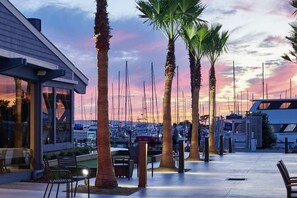 A waterfront patio with palm trees, outdoor seating, and a marina in the background. - Bayfront Stay Near Berkeley Marina + Dining & Pool (Berkeley)