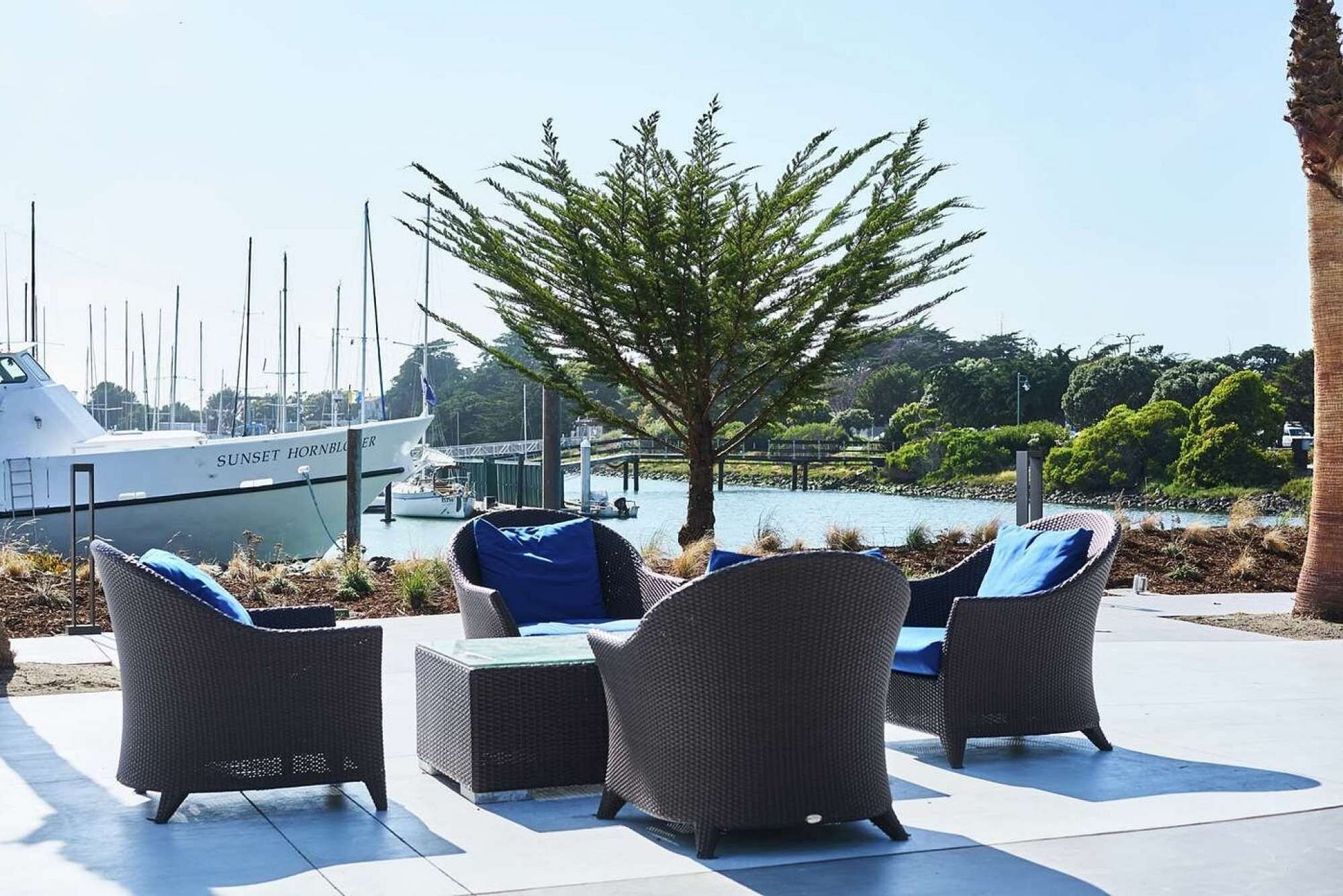 A patio with wicker furniture and a view of a marina with boats.