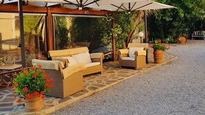 A covered outdoor seating area with wicker furniture and potted plants. - Appartamento Lavanda (San Vincenzo)