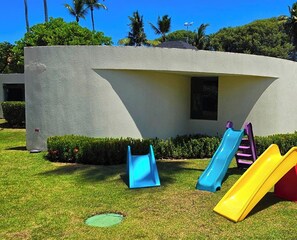 Ein Spielplatz mit Rutschen und einem Gebäude im Hintergrund.