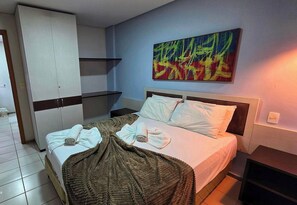 Une chambre d’hôtel avec un lit, une armoire, un tableau et un téléviseur.