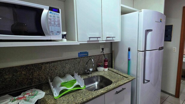 Una cocina equipada con microondas, refrigerador, lavaplatos y alacenas.