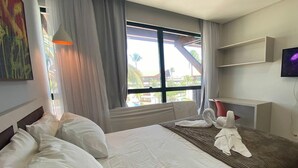 Una habitación de hotel con una cama grande, un televisor de pantalla plana, una ventana con cortinas y un cuadro en la pared.