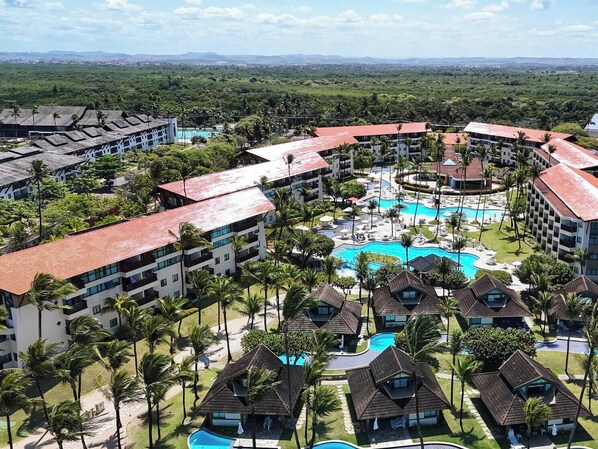 Ein Resort mit mehreren Gebäuden, einem zentralen Poolbereich und umliegender Bepflanzung.