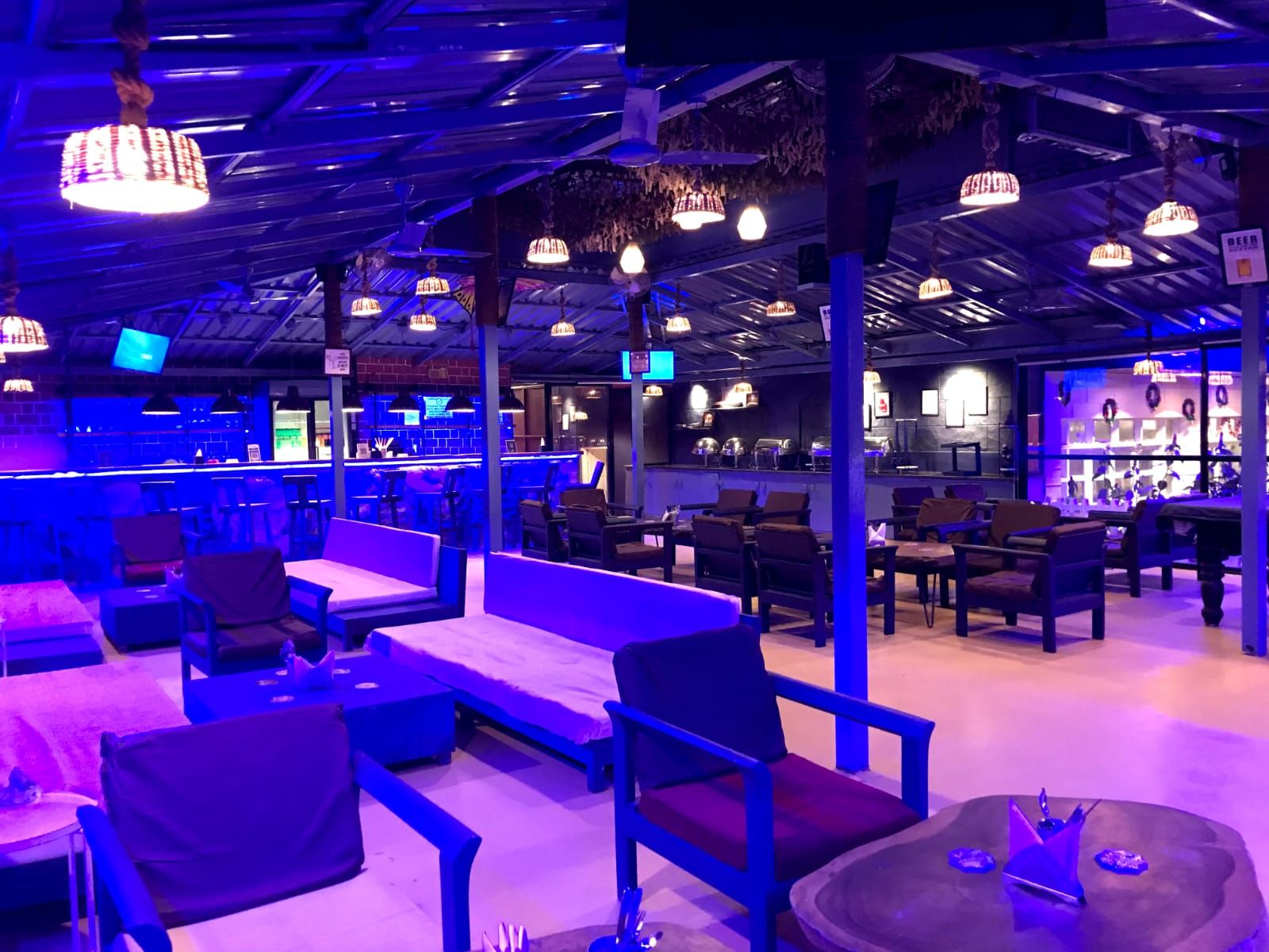 An indoor seating area with tables and chairs, a bar area with a counter, and hanging pendant lights.