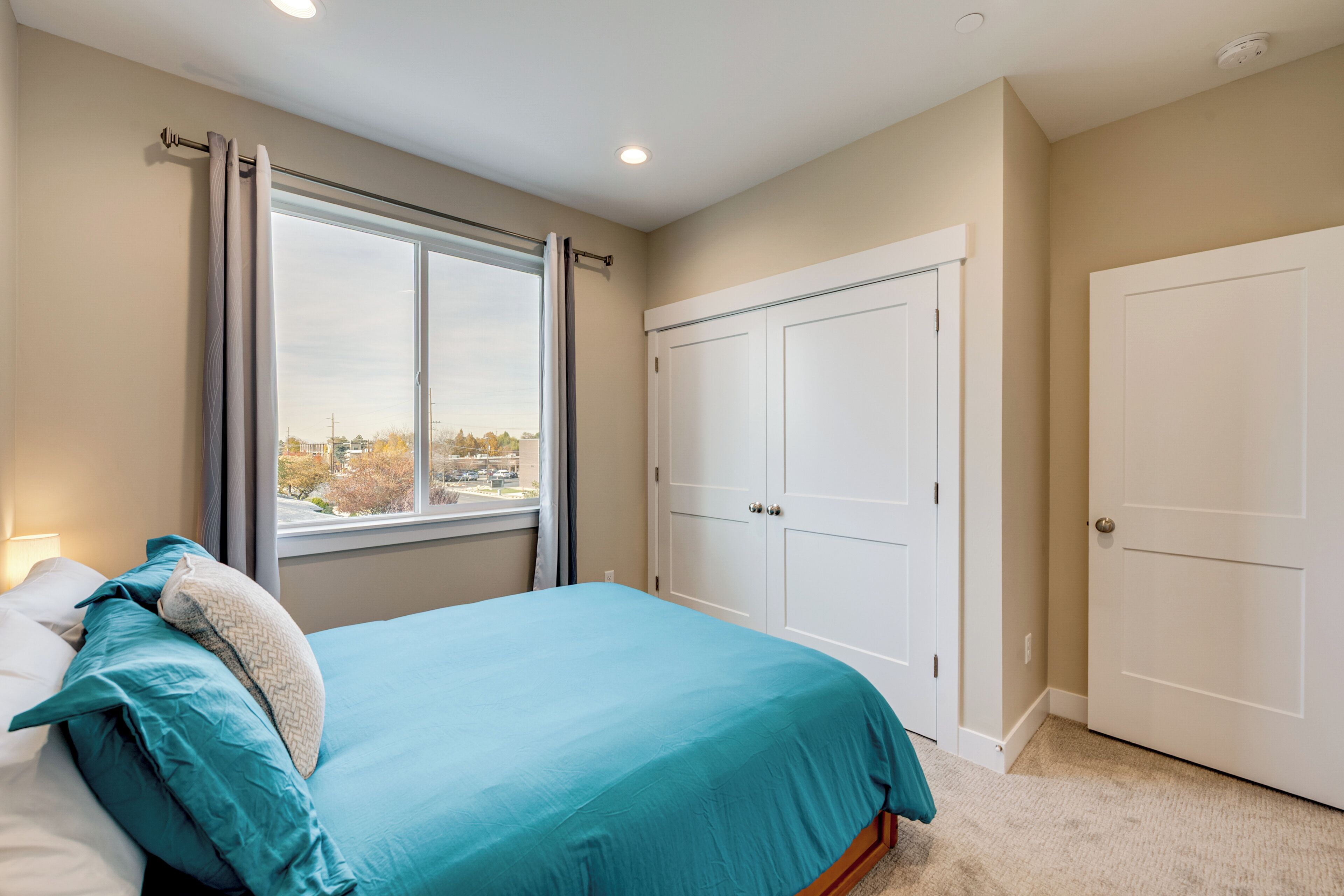 A bedroom with a bed, a window, a wardrobe, and a door.