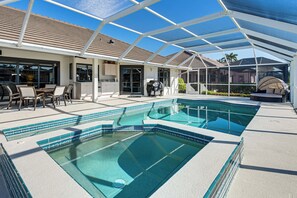 Una piscina cubierta al aire libre con zona de patio, mobiliario y un paseo techado.
