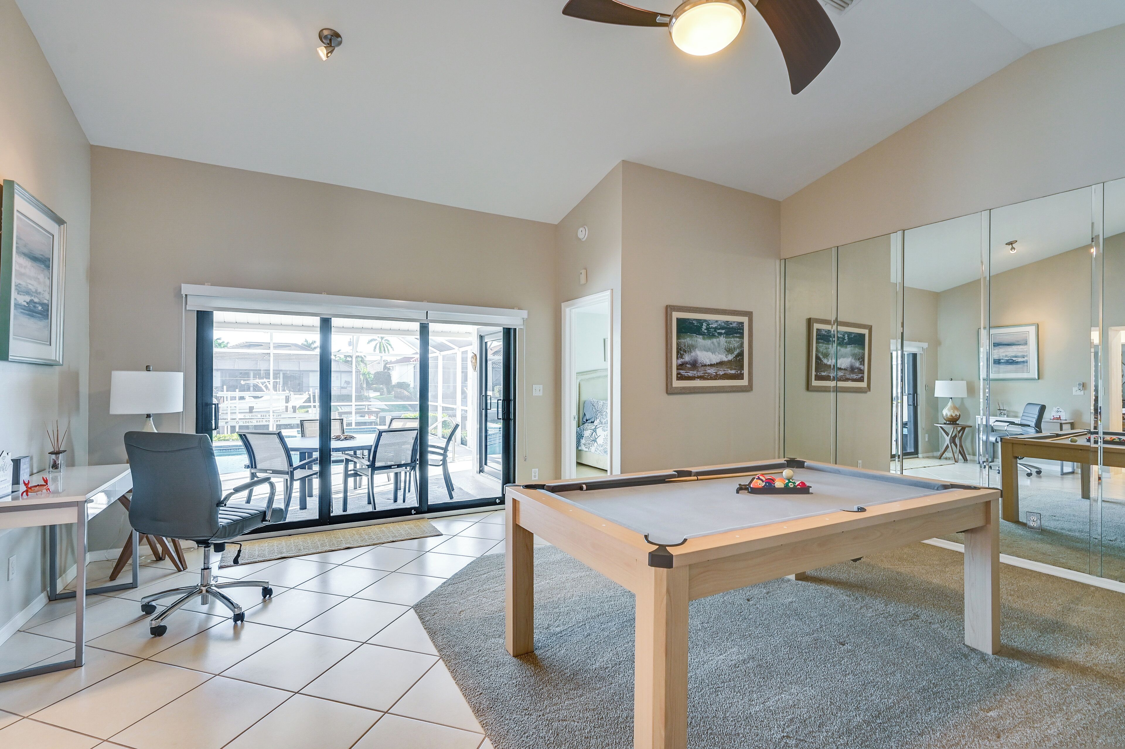 Een moderne kamer met een pooltafel, een bureaustoel en een groot raam met uitzicht op de omgeving.