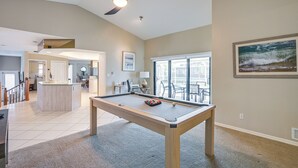 A spacious room with a pool table, a ceiling fan, and a large window providing a view of the outdoors. - Canal-front Luxury Pool, Boat & Relax in Marco (Marco Island)