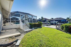 A modern house with a glass-enclosed patio, a swimming pool, and a well-maintained lawn. - Marco Island Waterfront Home w/ Pool & Boat Dock (Marco Island)