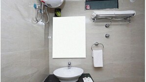 Un baño con lavamanos, espejo, toallero y cabezal de ducha.