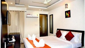 Habitación de hotel con cama, mesita de noche, lámpara, espejo y puerta.