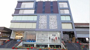 Un edificio moderno con fachada de vidrio, una escalera que conduce a la entrada y un letrero que dice "TIRUPATI CAR ZONE".
