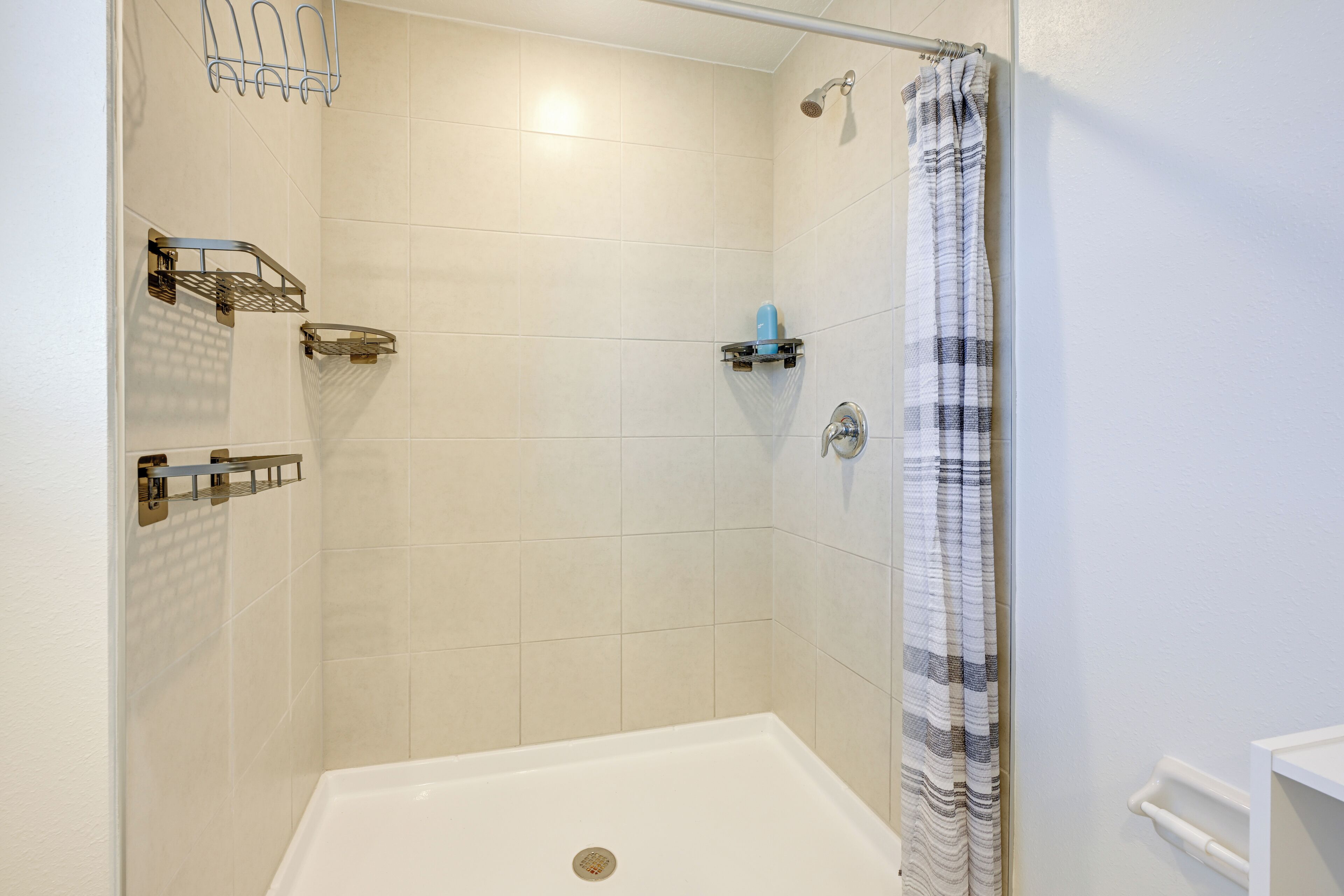 Une douche avec une porte en verre, un pommeau de douche et un porte-serviettes.