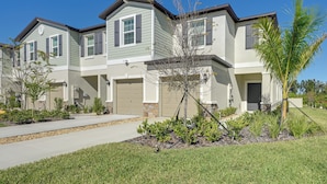 A row of townhouses with attached garages, a well-maintained lawn, and a small tree in the front yard.