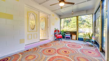 A room with a patterned floor, a ceiling fan, and a large window with a view of greenery.