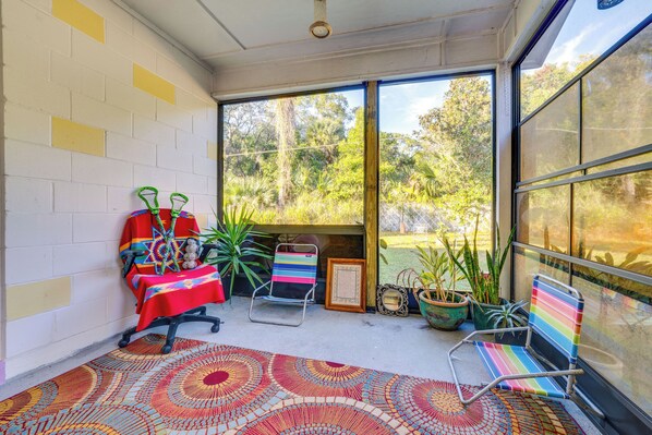 A sunlit room with a patterned rug, a table with a colorful tablecloth, two chairs, and potted plants. - 1 Mi to Historic Dtwn Sanford! Pet-friendly Unit (Sanford)