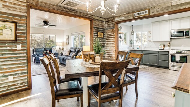 A rustic dining area with wooden chairs and a table, a kitchen with white cabinets and stainless steel appliances, and a ceiling fan. - 2 Mi to Clear Lake: Pet-friendly Lakeport Retreat! (Lakeport)