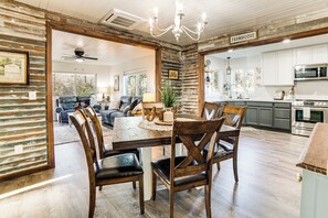 A rustic dining area with wooden chairs and a table, a kitchen with white cabinets and stainless steel appliances, and a ceiling fan. - 2 Mi to Clear Lake: Pet-friendly Lakeport Retreat! (Lakeport)