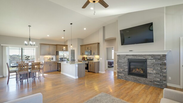 A spacious living area with hardwood flooring, a fireplace, a TV mounted on the wall, and a dining area with wooden chairs and a table. - < 1 Mi to Rio Grande Trails: Quiet Alamosa Escape (Alamosa)