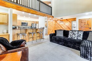 A spacious living area with a high ceiling, a wooden staircase, and a kitchen with modern appliances. - 1 Mi to Golf Course: Wfh-friendly Pinetop Retreat (Pinetop)