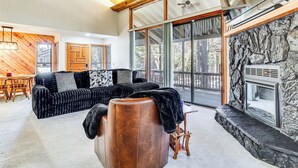 A modern living room with a sectional sofa, a leather ottoman, and a stone fireplace. - 1 Mi to Golf Course: Wfh-friendly Pinetop Retreat (Pinetop)