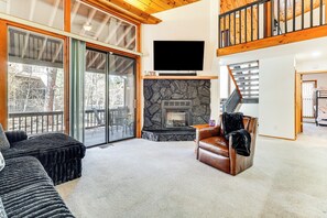 A spacious living room with a stone fireplace, a large flat-screen TV, and a cozy leather armchair. - 1 Mi to Golf Course: Wfh-friendly Pinetop Retreat (Pinetop)