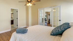 A bedroom with a large bed, a ceiling fan, and a view of the kitchen through an open door. - Apopka Family Home w/ Yard, 13 Mi to Dtwn Orlando (Apopka)