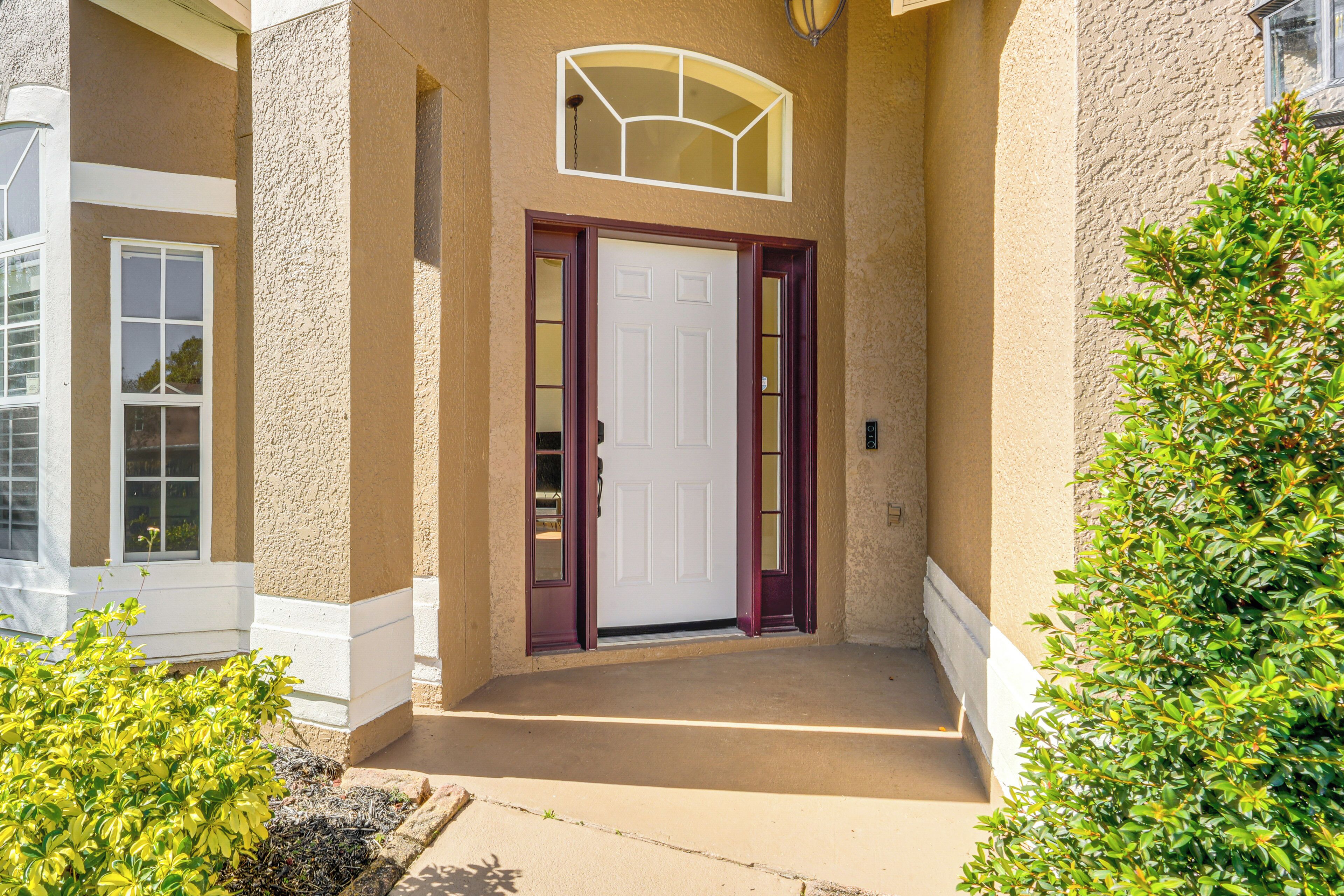 A beige stucco house with a white door, a small porch, and a window with a white frame.