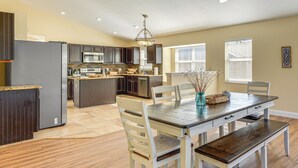 A modern kitchen with dark cabinets, a central island, and a dining area with a wooden table and chairs. - Apopka Family Home w/ Yard, 13 Mi to Dtwn Orlando (Apopka)